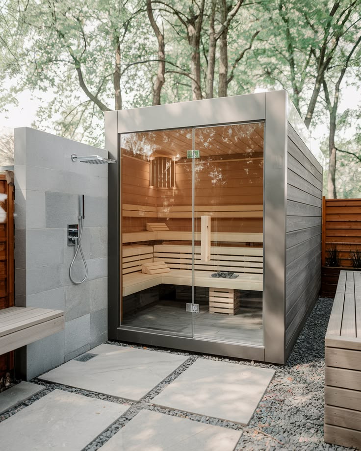 Modern glass-fronted sauna with outdoor shower and integrated landscape