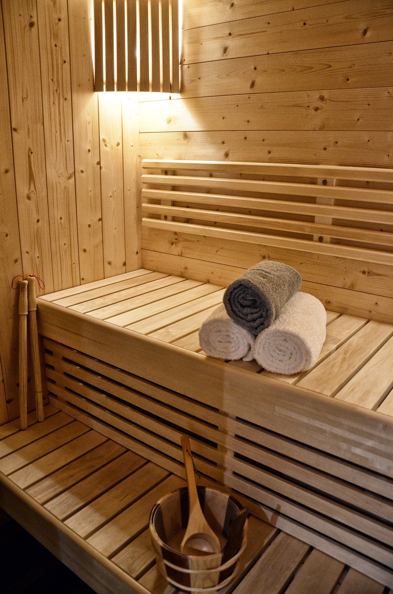 Warm cedar sauna interior with towels and ladle